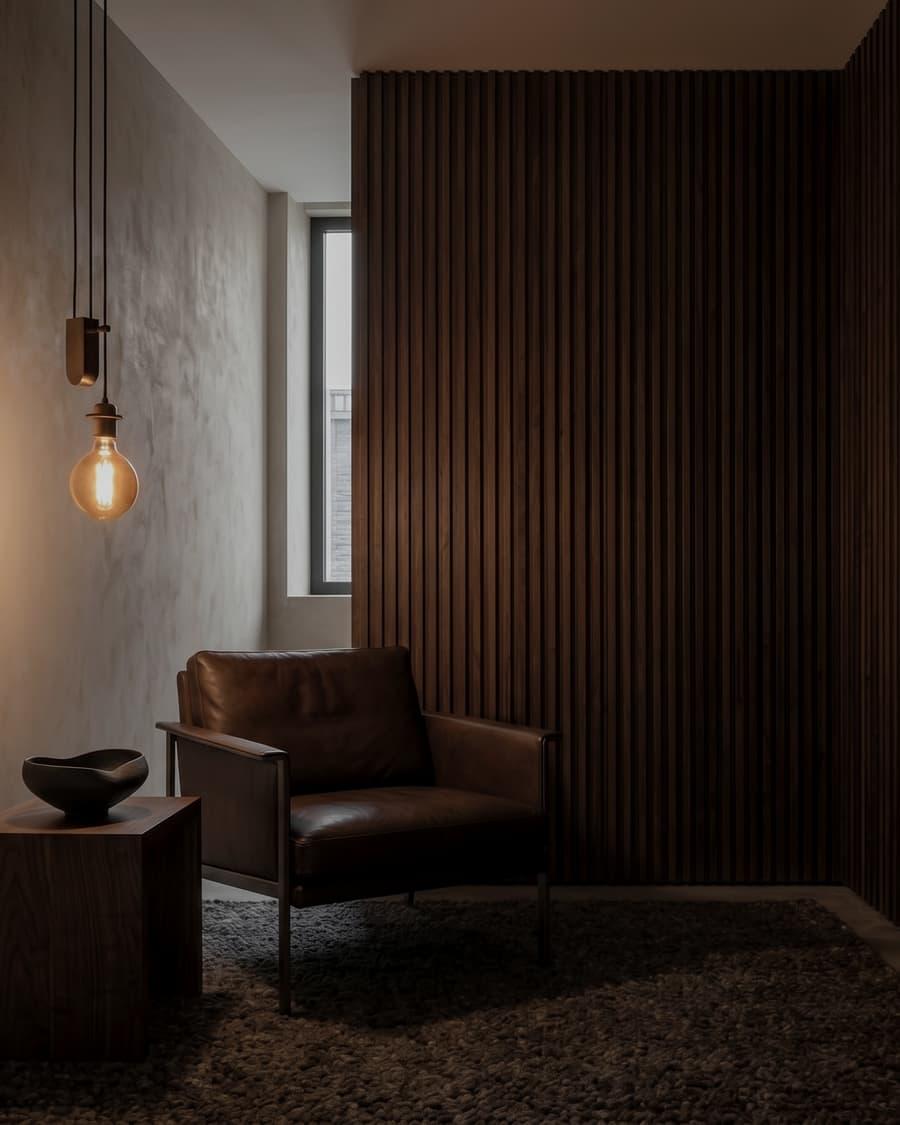 A subdued interior corner with a chair, wood paneling, and warm architectural light